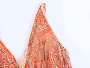 Detail of bohemian paisley print dress featuring delicate pink lace trim and thin straps