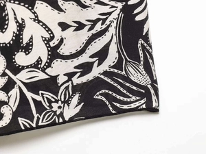 Dettaglio della stampa floreale su tessuto nero con cuciture decorative sul vestito a campana