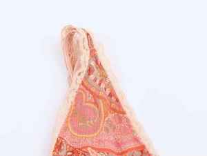 Detail of bohemian paisley print fabric with delicate peach lace trim on the neckline