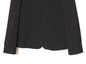 Detail of cross hem and buttoned cuffs on a black minimalist stand collar blazer