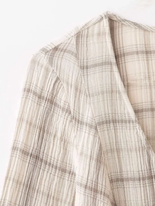 Détail du col en V et du tissu gaufré à carreaux beige sur une robe courte légère