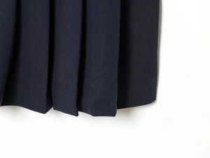 Detail shot of the crisp pleats and durable twill fabric on this navy sleeveless dress