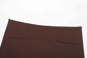 Gros plan de la fermeture éclair invisible et du tissu marron foncé de la mini-jupe