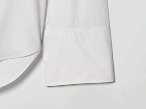 Détails des poignets larges et de l'ourlet arrondi sur cette chemise blanche