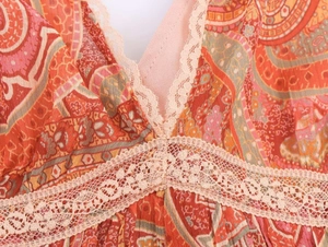 Detail of bohemian paisley print dress featuring V-neckline and cream lace trim details
