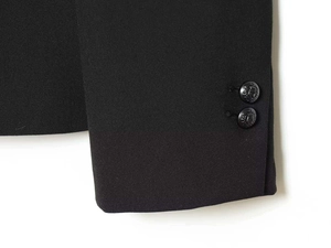 Detail of black blazer cuff featuring ornate crest buttons and twill fabric texture