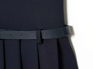 Detailed macro view of navy blue pleated dress fabric with a slim matching leather belt