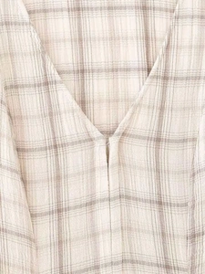 Gros plan sur la texture à carreaux beige et le col en V d'une robe minimaliste