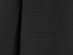 Detail of premium black woven fabric featuring two neat parallel welt pockets on a blazer