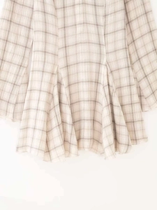Détail de la robe à carreaux beige clair montrant la texture du tissu et l'ourlet fluide