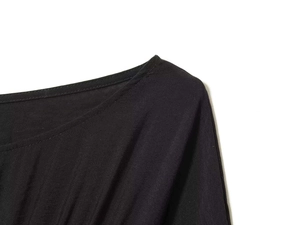 Close-up detail of the smooth neckline and refined stitching on a black pleated dress