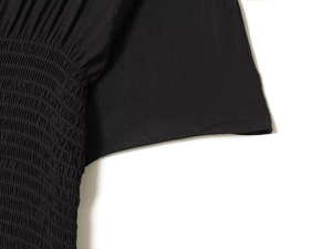 Macro detail of elastic smocking stitch and fabric texture on a black pleated dress