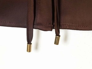 Detailed close-up of brown satin fabric texture with drawstring and gold metal aglets