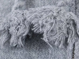 Makroansicht der grauen Strickjacke mit weichen Mohair-Schlingen und Metallreißverschluss