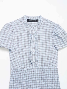Detail of light blue plaid dress showing smocked waist and ruffled front placket detail