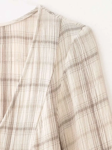 Gros plan du tissu beige à carreaux texturé seersucker avec coutures précises à l'épaule