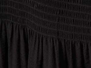 Detailed macro view of black smocking fabric with elastic pleated texture on the waistline