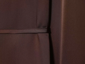 Macro detail of the dark brown satin fabric with fine stitching and smooth silk-like texture