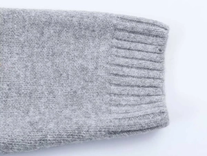 Detailaufnahme der grauen Strickjacke mit Sternenmuster, Textur und Rippbündchen