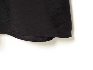 Close-up of pleated black fabric texture and clean hem stitching on a summer dress