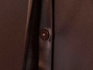 Detail of satin texture fabric in chocolate brown with a matching resin button