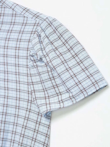 Detail showing the fine light blue plaid fabric texture and stitching on the shirt shoulder