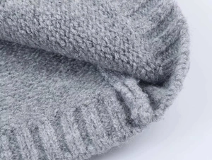 Makroaufnahme von grauem Jacquard-Strickstoff mit weicher Wolltextur und Rippbündchen