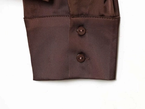 Close-up of brown satin shirt cuff featuring two matching buttons and smooth texture