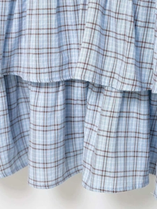 Close-up of light blue checkered tiered fabric detail with brown plaid pattern