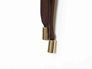 Close-up of dark brown satin drawstring with cylindrical gold metal tips and caps