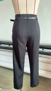 Rear view of black high-waisted trousers with matching slim belt and tailored waist darts