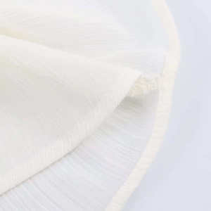 Close-up of white ruffled chiffon fabric with vertical texture and delicate hemmed edges