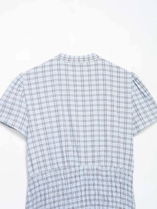 Detail of light blue plaid dress showing smocked elastic waist and puff sleeve texture
