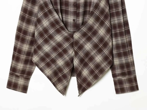 Detail der langärmeligen Karo-Bluse mit asymmetrischem, plissiertem Saum und Knöpfen