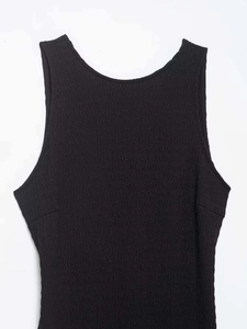 Dettaglio del vestito nero senza maniche che mostra il tessuto operato e lo scollo rotondo