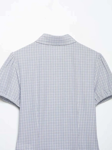 Détail du motif à carreaux bleu et blanc sur la manche bouffante et le dos de la chemise
