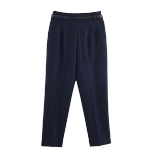 Detail of high-waisted navy trousers featuring slim pleats and matching thin belt