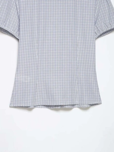 Détail du motif à carreaux bleus et blancs sur cette chemise à manches bouffantes