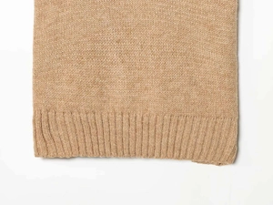 Macro detail of khaki knit top featuring a fine texture and ribbed hem edge