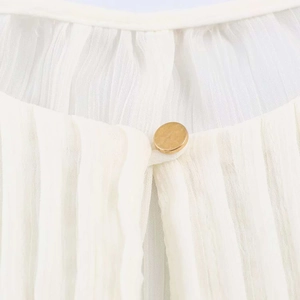 Detail of pleated chiffon texture with a decorative gold round button on the neckline
