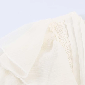 Detailed close-up of ivory ruffle blouse with intricate crochet lace and vertical textures
