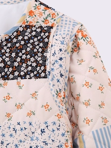 Detail view of diamond quilted cotton jacket with floral patchwork and blue piping
