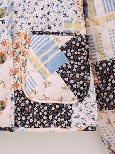 Detail shot of a quilted cotton jacket featuring mixed floral and plaid patchwork design