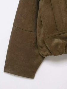 Gros plan sur la veste en daim vert olive montrant les coutures et la texture du tissu mat