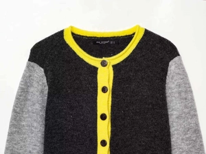 Close-up of contrast trim knit cardigan with yellow ribbed neckline and tortoise buttons