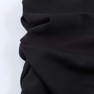 Close-up detail of the black lace dress fabric with intricate knitted texture and soft folds