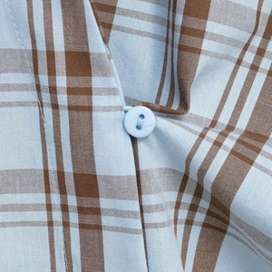 Klassisches hellblau-braun kariertes Hemd mit Details eines blauen Knopfes auf dem Stoff