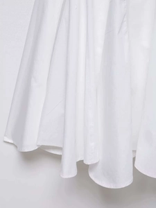Détail de l'ourlet plissé sur une robe d'été blanche avec un drapé de tissu lisse