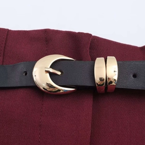 Detail of black leather belt with a polished gold crescent moon buckle and matching loops