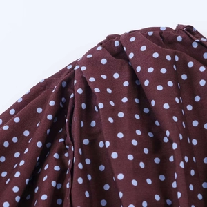Detalle de blusa marrón retro con lunares azules y diseño de manga farol plisada